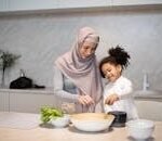 A joyful mother and daughter cooking together, sharing a special moment in the kitchen.